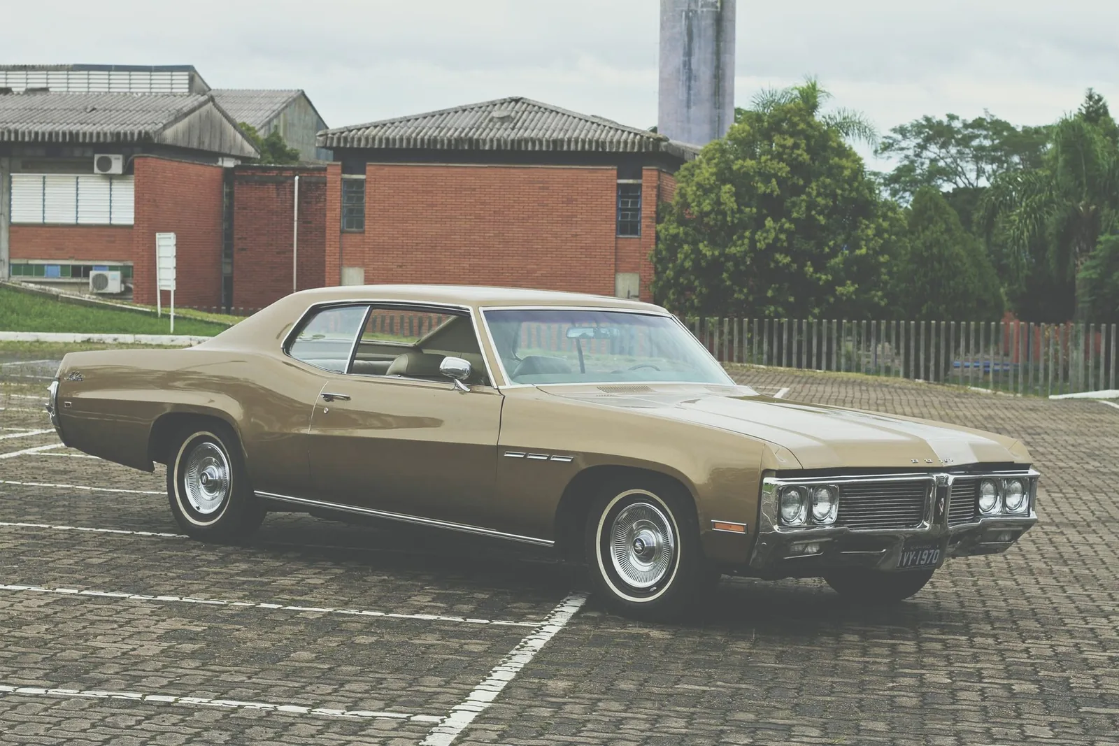 Buick LeSabre dourado restaurado, na frente de um galpão de tijolo